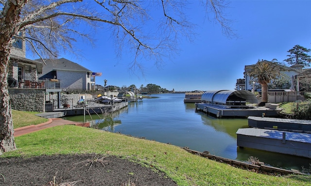 view of dock with a lawn and a water view