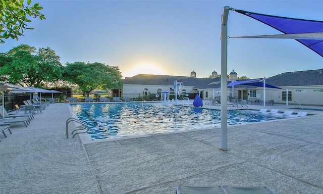 pool at dusk featuring a patio, a community pool, and fence