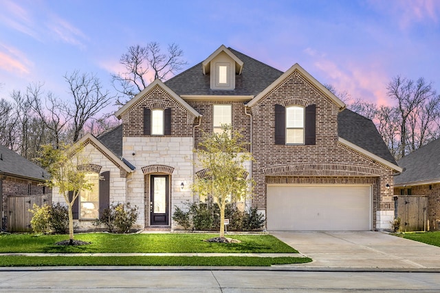 french country style house with brick siding, a lawn, concrete driveway, and a shingled roof