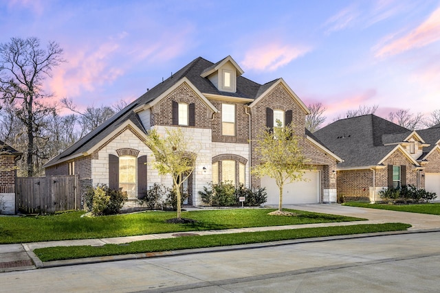 french country style house featuring fence, driveway, a yard, stone siding, and brick siding