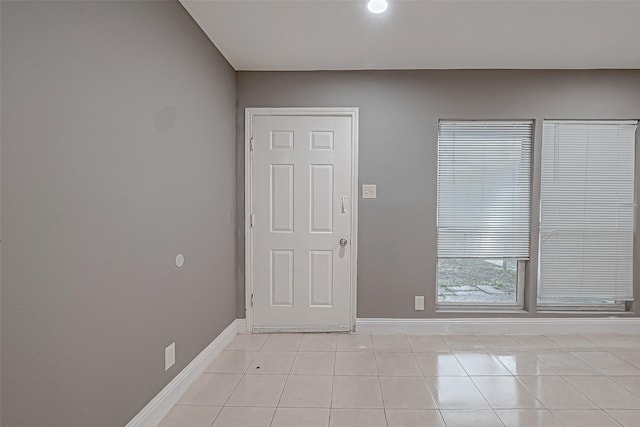 spare room featuring light tile patterned flooring and baseboards