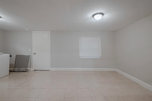 spare room with baseboards, a textured ceiling, and washer / dryer