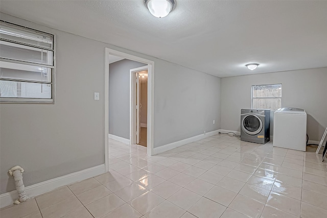 laundry area featuring light tile patterned floors, baseboards, and washing machine and dryer