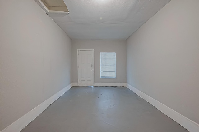 spare room featuring baseboards and concrete flooring