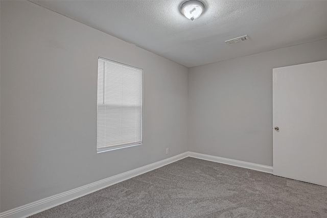 unfurnished room featuring baseboards, visible vents, dark colored carpet, and a textured ceiling