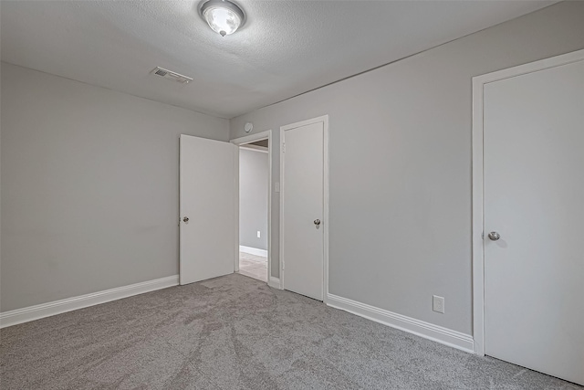 unfurnished bedroom featuring carpet flooring, baseboards, visible vents, and a textured ceiling