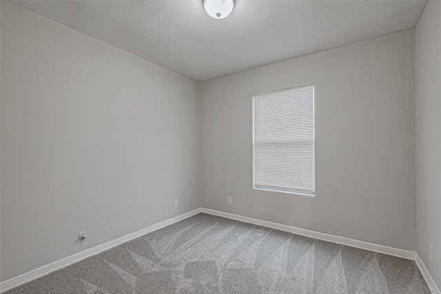 unfurnished room with a textured ceiling, baseboards, and dark colored carpet