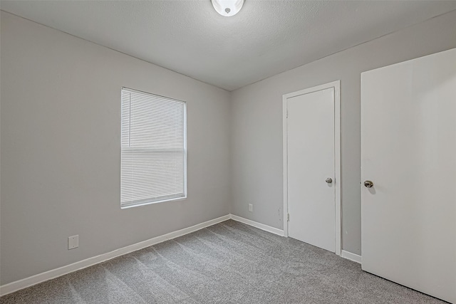 unfurnished room with baseboards, a textured ceiling, and carpet flooring