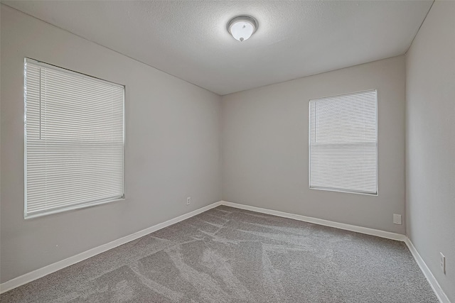 carpeted empty room with baseboards and a textured ceiling