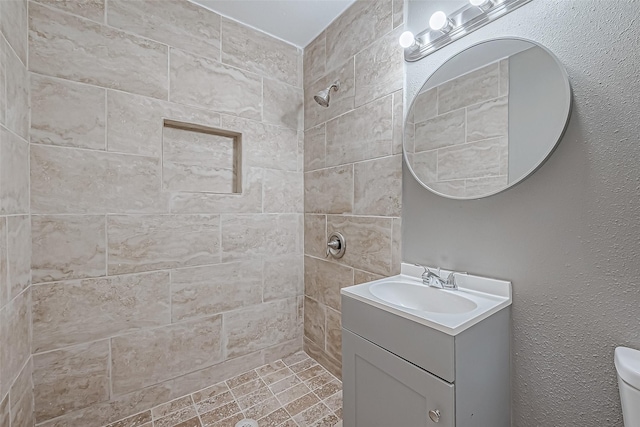 full bath featuring vanity, toilet, and tiled shower