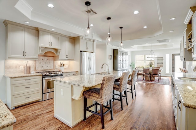 kitchen with visible vents, appliances with stainless steel finishes, a raised ceiling, and a sink