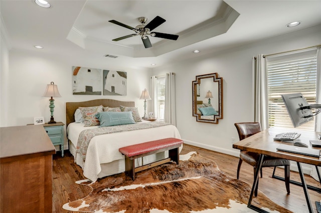 bedroom featuring crown molding, a raised ceiling, and wood finished floors