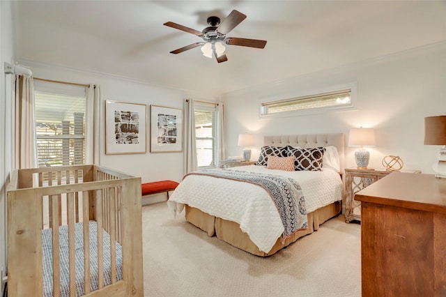 bedroom featuring light colored carpet, ornamental molding, and a ceiling fan