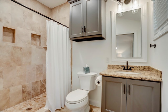 full bath with vanity, toilet, baseboards, and tiled shower