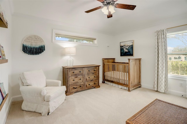 carpeted bedroom featuring ceiling fan, a crib, crown molding, and baseboards