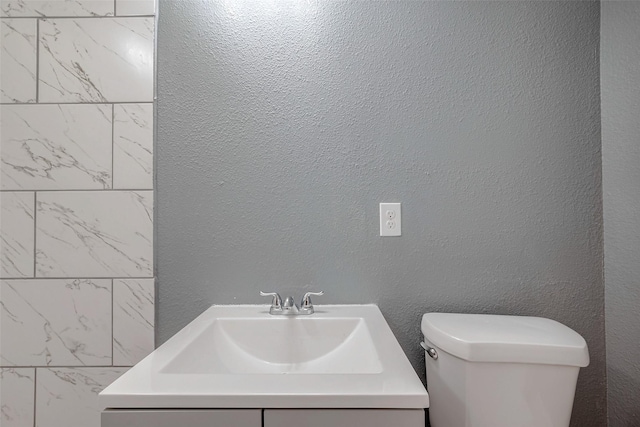 bathroom featuring vanity, toilet, and a textured wall