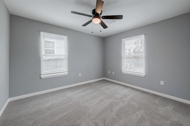 carpeted spare room featuring baseboards and ceiling fan