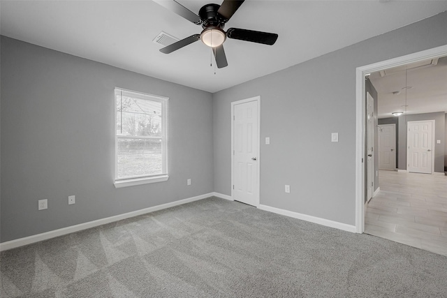 empty room featuring light colored carpet, attic access, baseboards, and ceiling fan