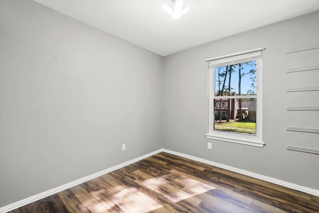 empty room with dark wood-type flooring and baseboards