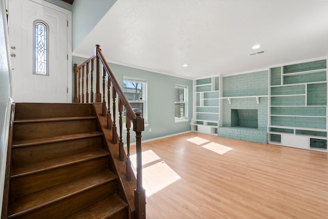 interior space with stairway, wood finished floors, visible vents, a fireplace, and crown molding