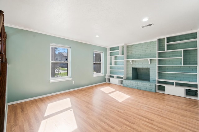 unfurnished living room with visible vents, wood finished floors, a fireplace, and crown molding