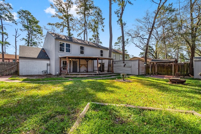 back of house with fence, a yard, a storage shed, an outdoor structure, and a wooden deck