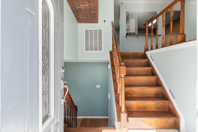 stairs featuring wood finished floors, visible vents, and baseboards