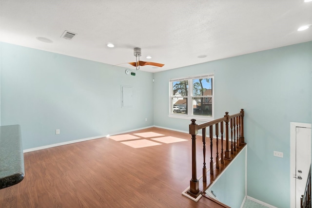 spare room featuring wood finished floors, visible vents, and baseboards