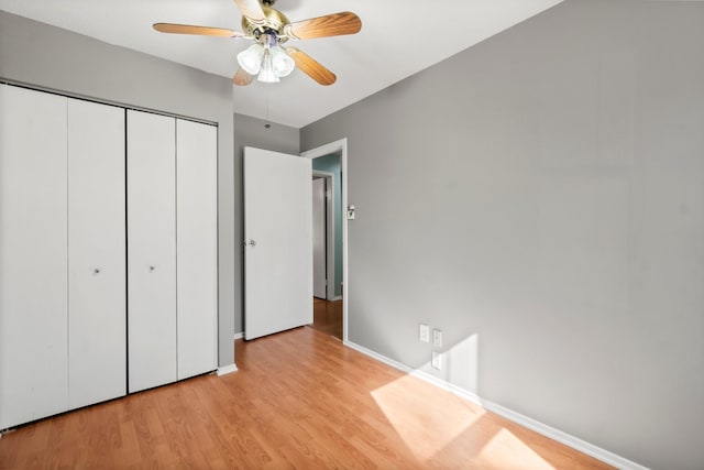 unfurnished bedroom with a ceiling fan, wood finished floors, a closet, and baseboards