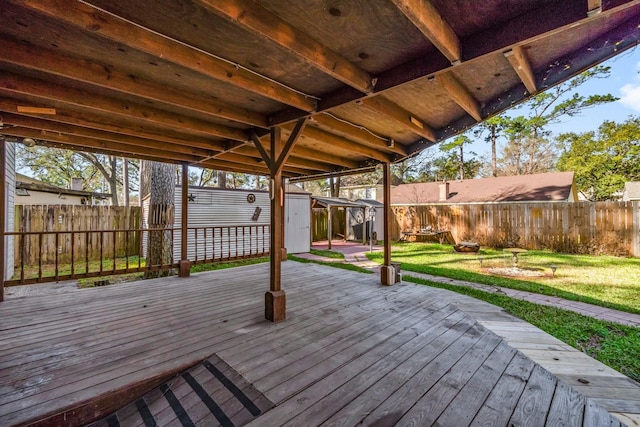 wooden deck with a storage unit, a fenced backyard, a lawn, and an outdoor structure