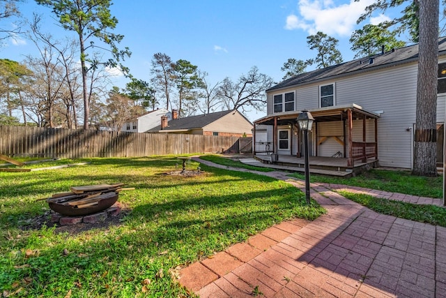 view of yard featuring a wooden deck, a fire pit, and a fenced backyard