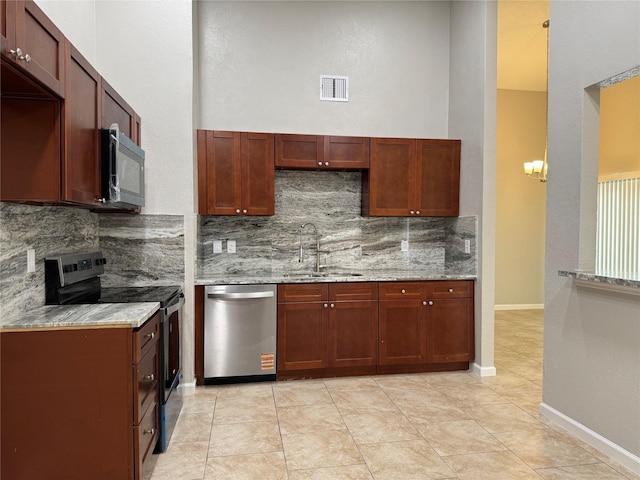 kitchen featuring light stone countertops, visible vents, a sink, decorative backsplash, and appliances with stainless steel finishes