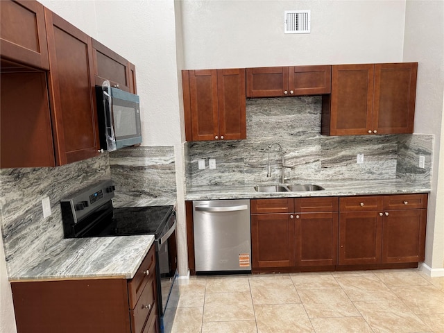 kitchen featuring light stone counters, visible vents, a sink, stainless steel appliances, and tasteful backsplash