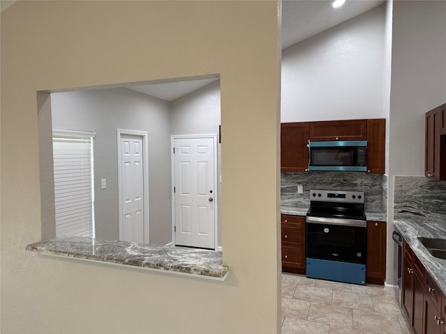 kitchen with a sink, backsplash, appliances with stainless steel finishes, and light stone countertops