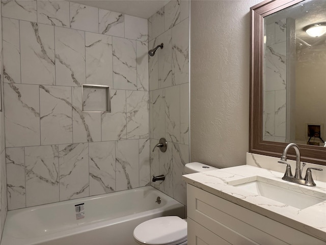 bathroom with vanity, toilet, a textured wall, and shower / bathtub combination