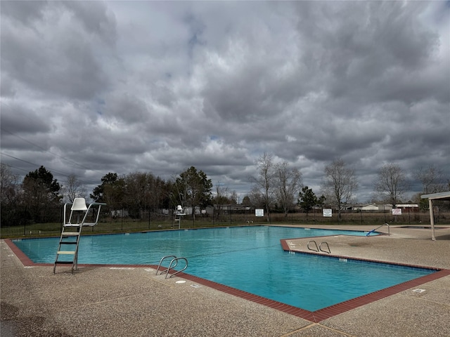 community pool with a patio area and fence