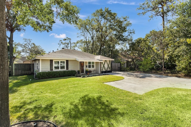 view of front of house featuring concrete driveway, fence, and a front yard