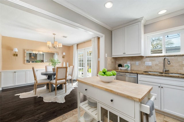 kitchen featuring a sink, wood counters, stainless steel dishwasher, french doors, and a healthy amount of sunlight