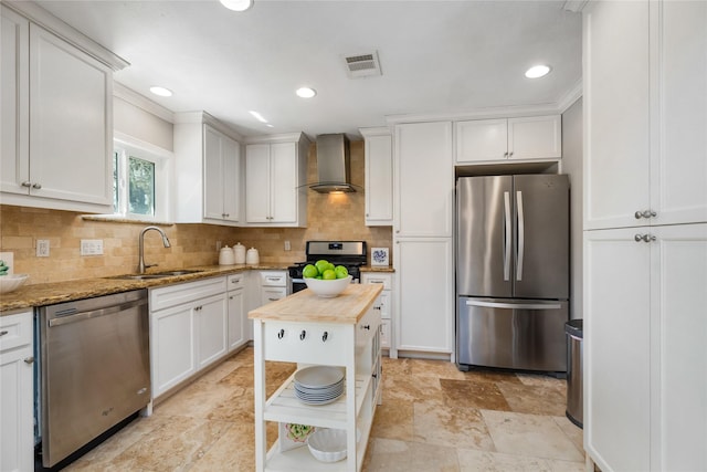 kitchen with visible vents, a sink, appliances with stainless steel finishes, wall chimney range hood, and backsplash