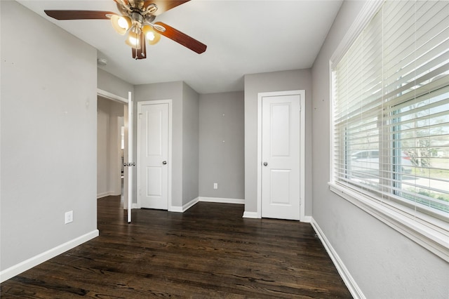 unfurnished bedroom with dark wood finished floors, a ceiling fan, and baseboards