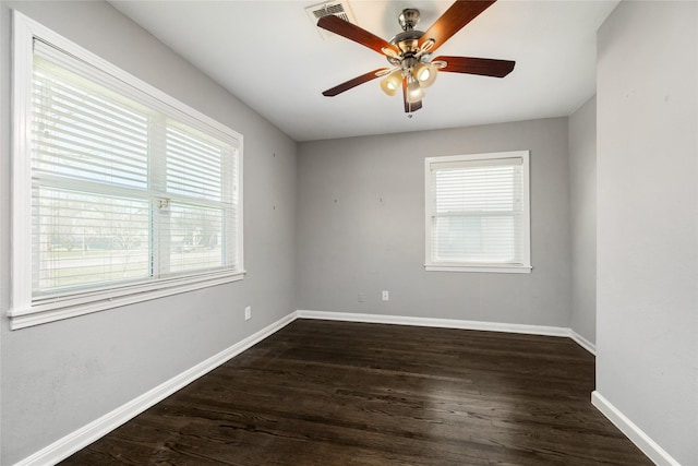 spare room featuring baseboards, plenty of natural light, dark wood-style floors, and a ceiling fan