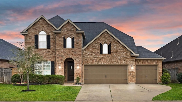 traditional-style house with brick siding, a garage, concrete driveway, and a front yard