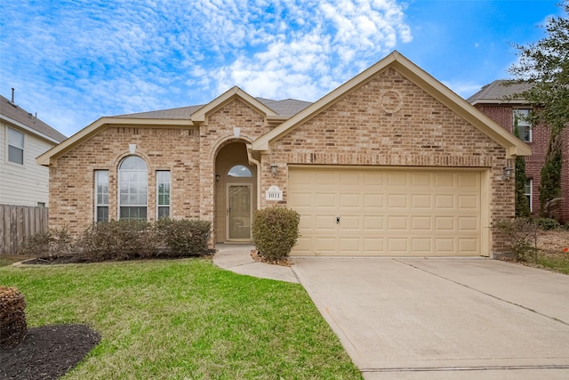 view of front facade featuring a front yard, fence, driveway, a garage, and brick siding