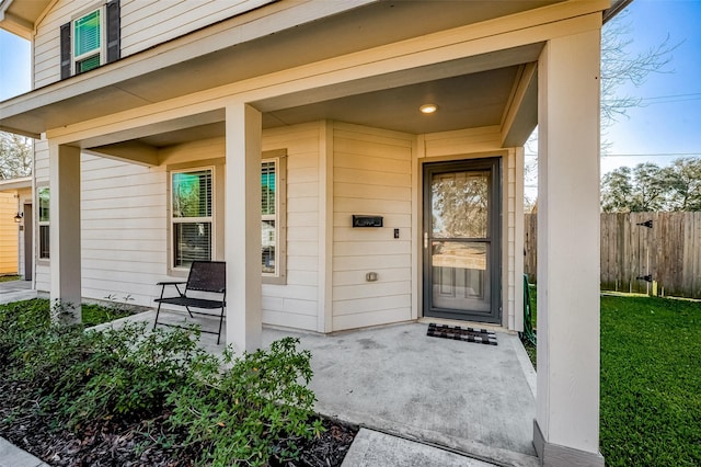 view of exterior entry with fence and covered porch