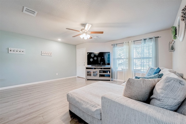 living area featuring a ceiling fan, baseboards, visible vents, and light wood-type flooring