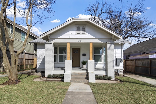 bungalow-style home featuring a front lawn, fence, and covered porch