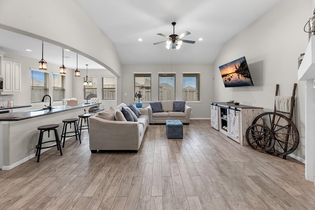 living area featuring a ceiling fan, recessed lighting, arched walkways, light wood-style floors, and baseboards