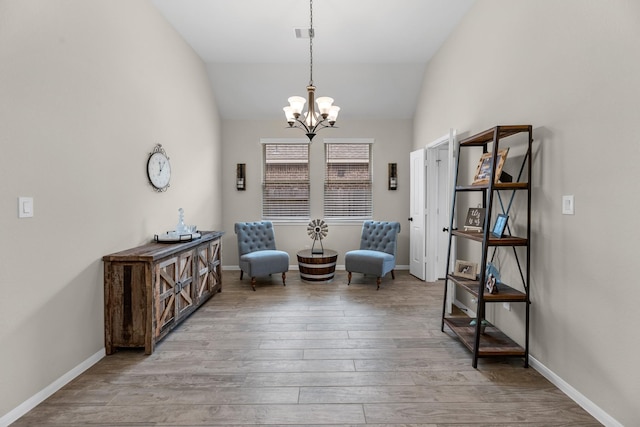 sitting room featuring lofted ceiling, wood finished floors, baseboards, and a chandelier