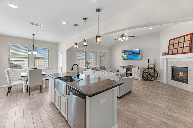 kitchen featuring light wood finished floors, a sink, open floor plan, and stainless steel dishwasher