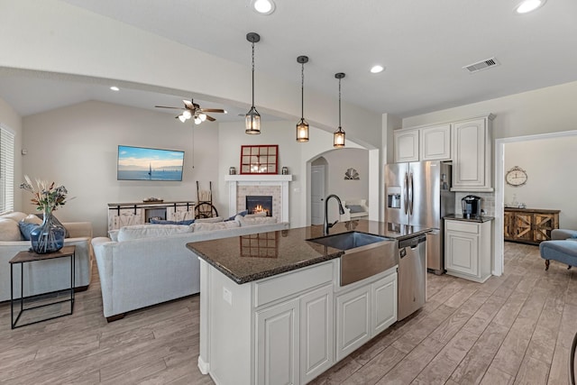 kitchen featuring visible vents, open floor plan, light wood-style flooring, stainless steel appliances, and a sink